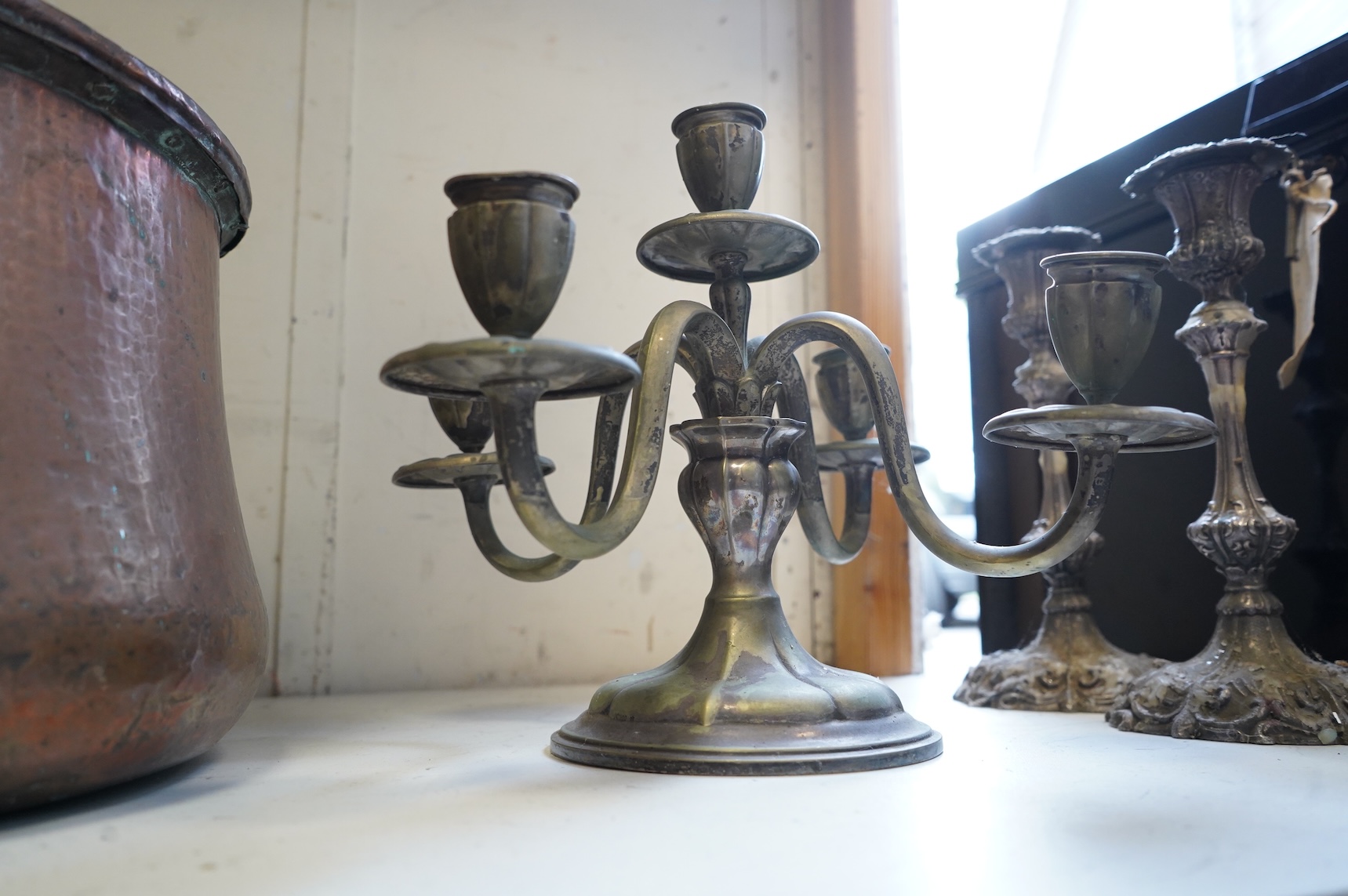 A pair of silver plated candlesticks, a four branch, three light candlestick and a copper cauldron